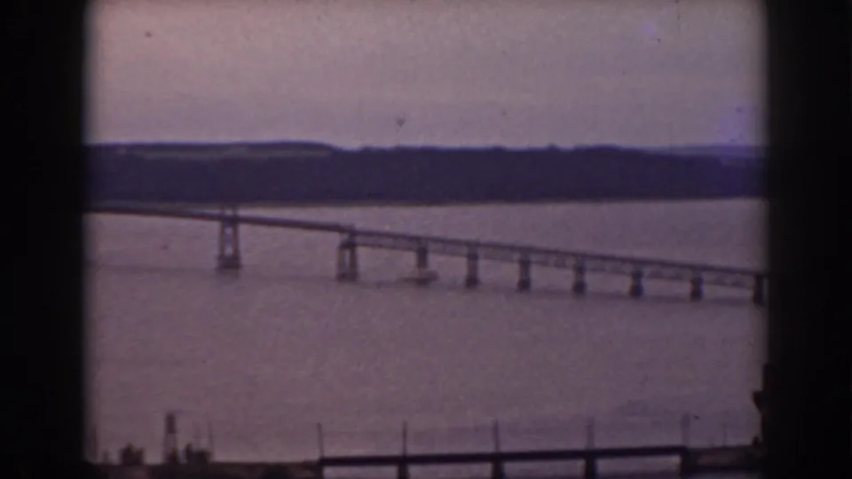 1938 8mm home-movie view of a long bridge over water near Mount Washington, New Hampshire, framed by a dark window edge.