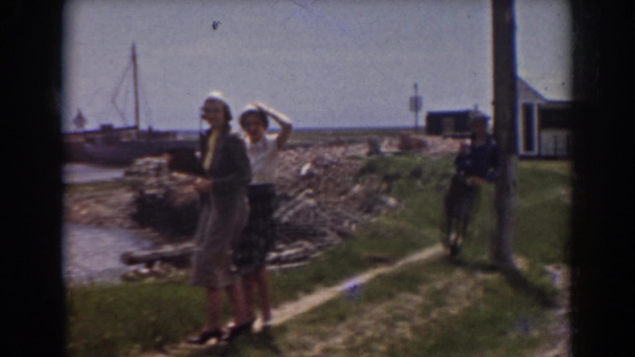 Two women in 1930s-style clothing stand near a rocky shore and boats in the Mount Washington, New Hampshire clip.
