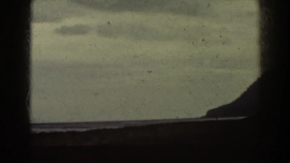 1938 Mount Washington area frame with a dark window crossbar, muted sky and water, and a low ridge silhouette entering from the right.