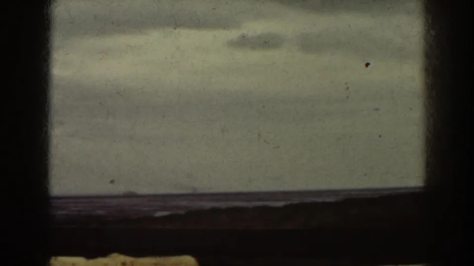 1938 Mount Washington area frame showing a dark window grid around a soft, grainy view of calm water, cloudy sky, and a faint distant horizon.