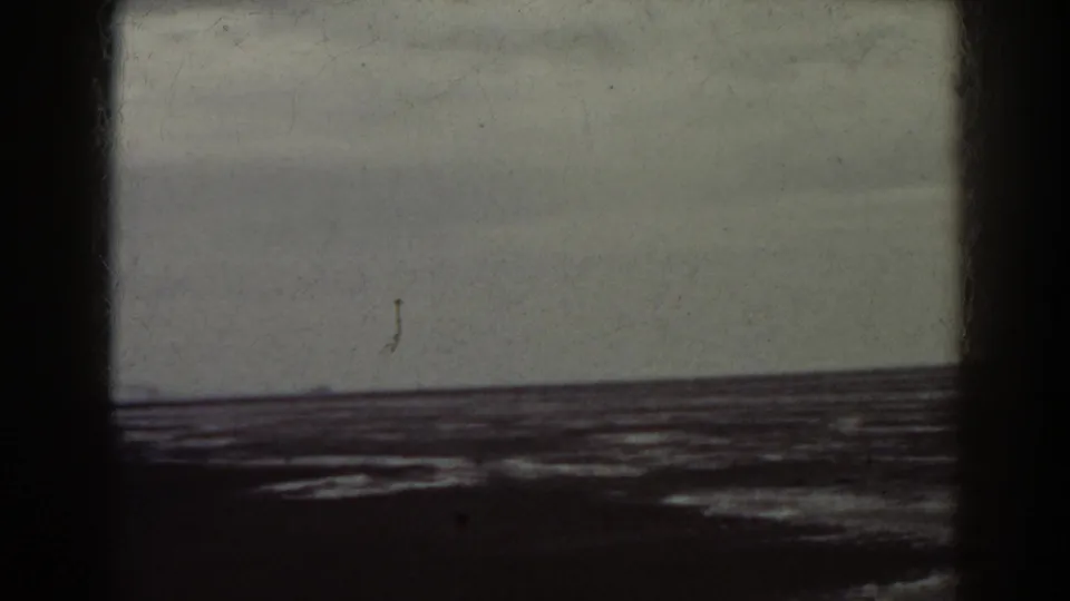 1938 8mm home-movie frame associated with Mount Washington, New Hampshire, showing muted sea and shoreline under an overcast sky.
