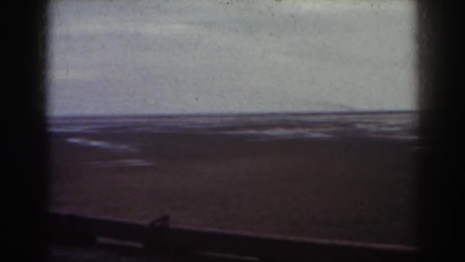 1938 Mount Washington home-movie frame showing a muted snowy expanse beneath an overcast sky, with dark gate edges and a low foreground rail.