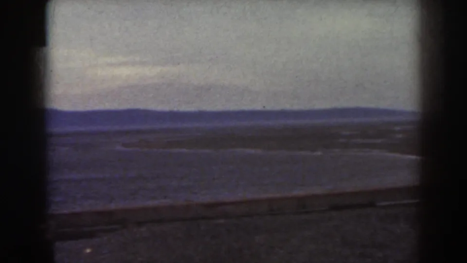 Final 1938 Mount Washington frame showing a low overlook barrier, broad plain, distant ridge, and muted cloudy sky.