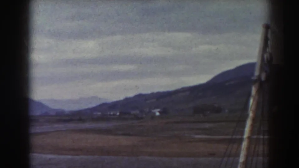 1938 8mm view near Mount Washington showing water, open brown fields, distant hills, and dark window-like borders.