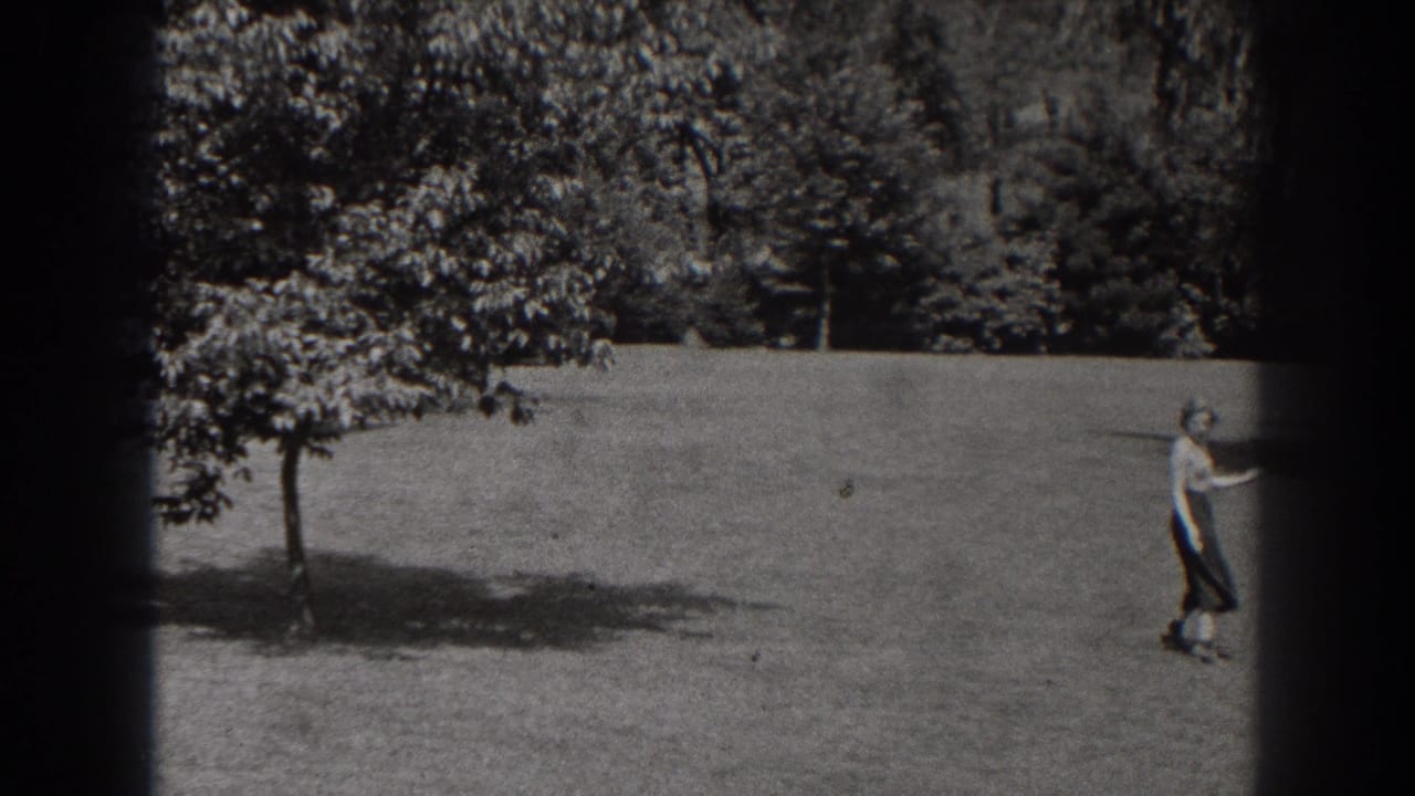 Woman walking across a grassy park field near trees.