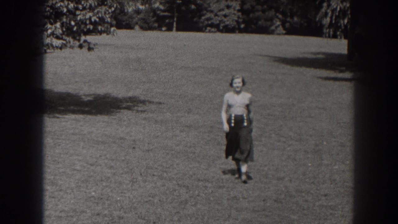 A woman in a blouse and dark skirt faces the camera on an open lawn in the 1938 New Jersey park scene.
