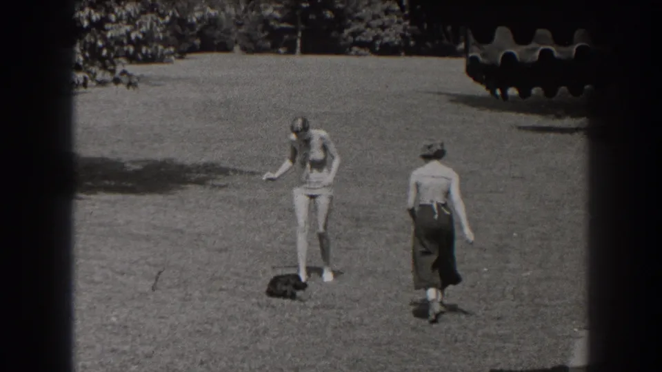 Two women share the lawn near the end of the 1938 New Jersey clip, one bending or gesturing while the other walks away.