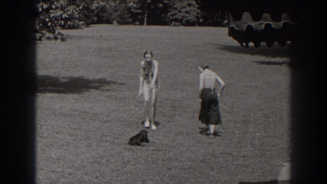 A 1938 New Jersey home-movie frame shows two young women separated on a lawn, with a small black dog sitting or standing near the center.