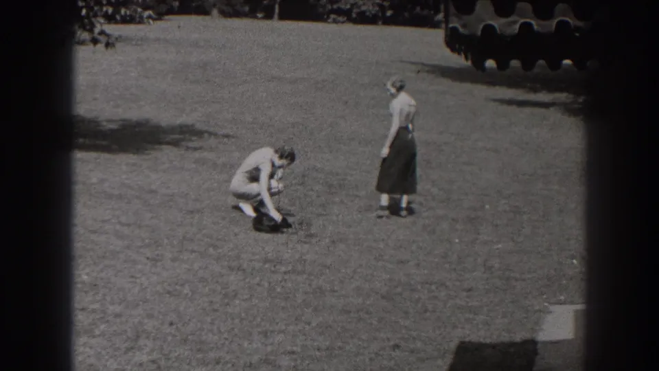 The man crouches beside the small dark dog in the New Jersey park scene as the woman remains standing a short distance away.
