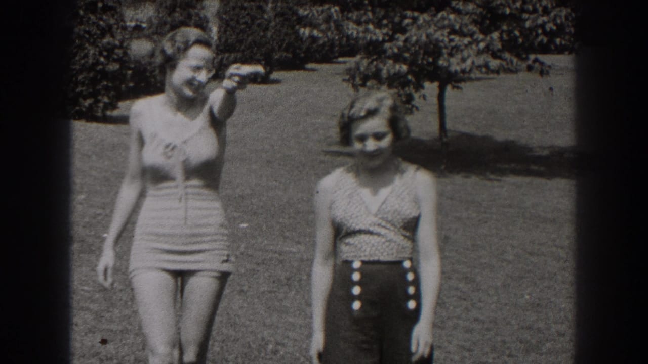 Two women in vintage swimwear walk across a lawn toward the camera.