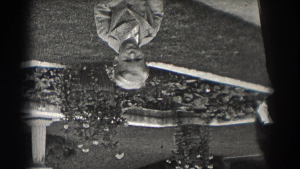 1938 New Jersey home-movie still with an upside-down reflected light-suited person, a nearby dark-clothed figure, and soft outdoor detail.