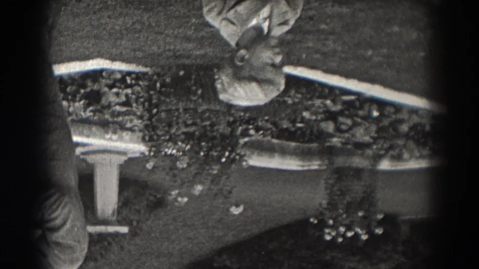 Inverted 1938 New Jersey 8mm frame showing two male figures near a small fountain or garden water feature.