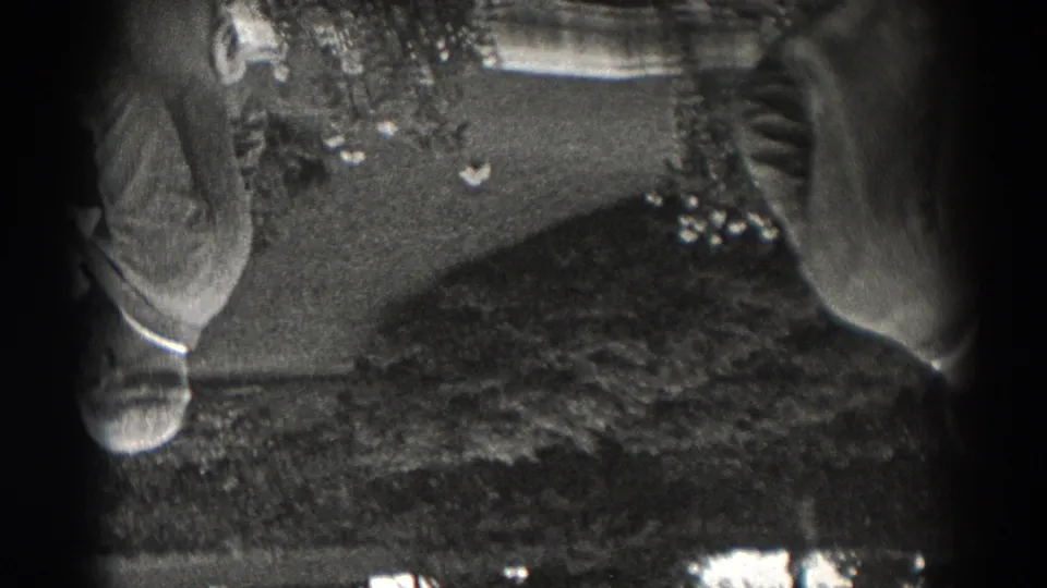1938 New Jersey 8mm frame, upside down, showing an adult in outdoor clothing on a lawn near shrubs, with another figure partly blocking the view.