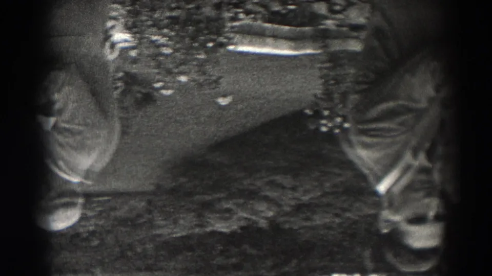 1938 New Jersey home-movie frame showing adult men in suits and brimmed hats near tables, with the view inverted and heavily vignetted.