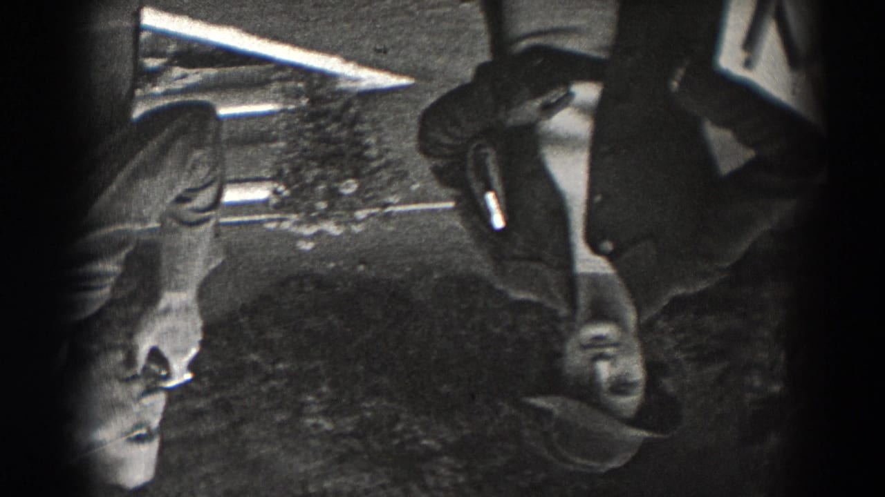 Inverted black-and-white 8mm frame of suited adult men standing near tables and chairs in the New Jersey restaurant gathering.
