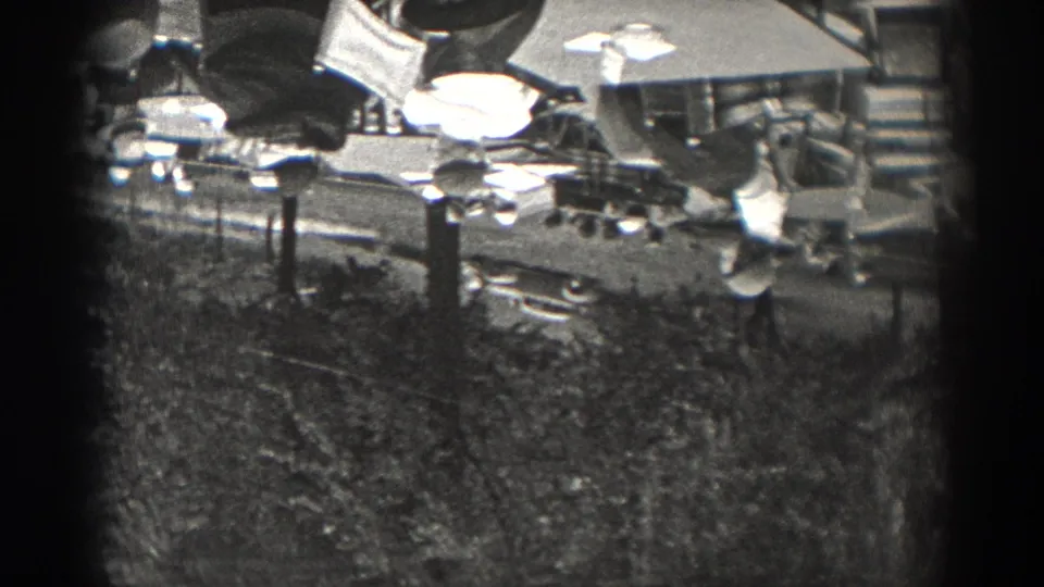 1938 New Jersey 8mm frame showing round tables, chairs, plates or tableware, and partial adult figures in a casual restaurant or patio setting.