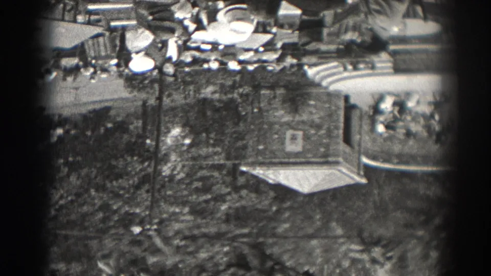 Elevated 1938 New Jersey frame showing an outdoor gathering area, trees, lamp posts, a walkway, and a small roofed structure at the side.