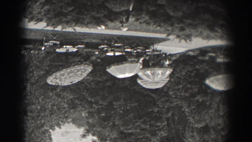 1938 New Jersey 8mm frame showing garden tables and patterned umbrellas on grass beneath trees.