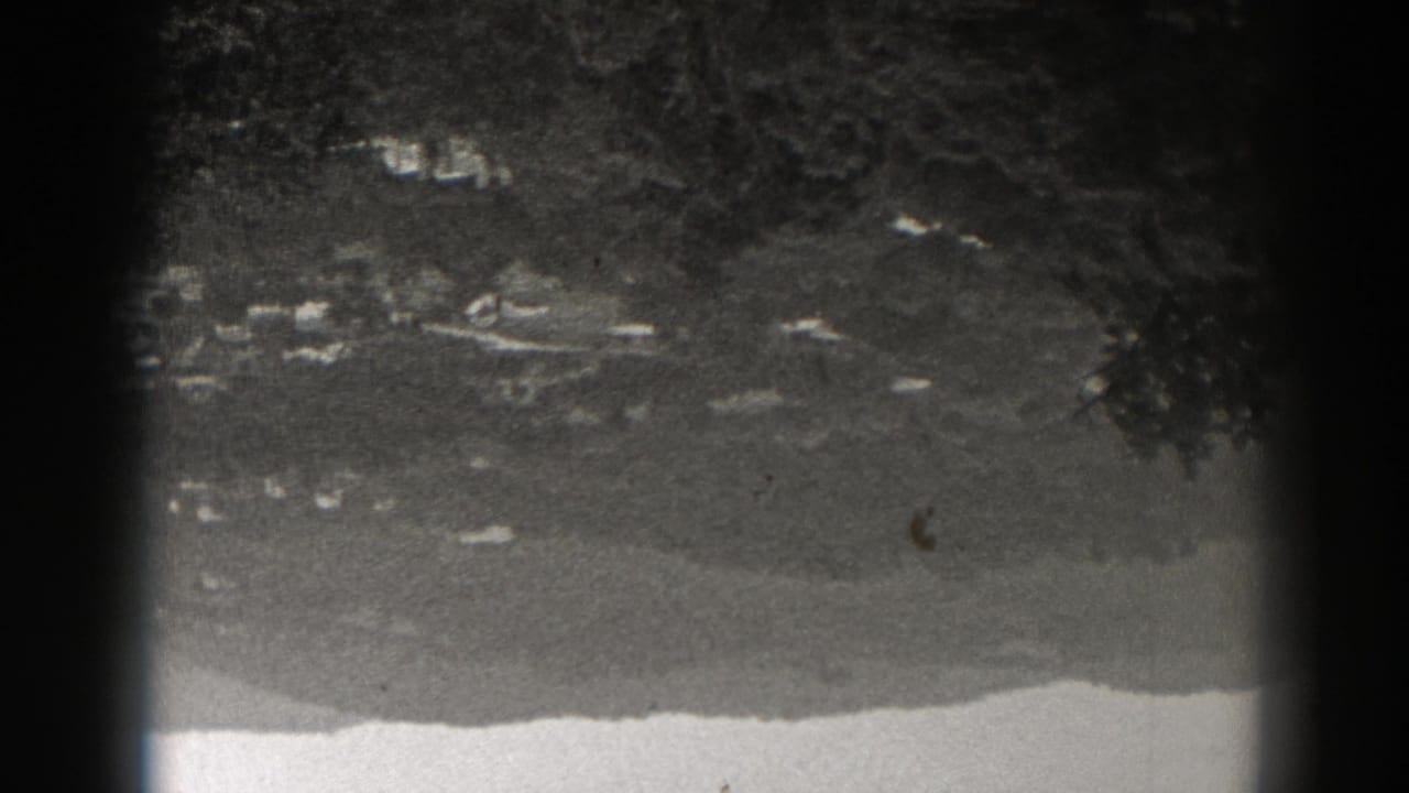 Upside-down black-and-white 8mm frame showing a New Jersey village area against wooded mountain terrain.