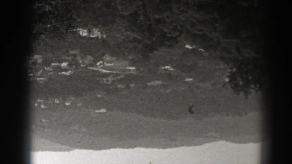 Upside-down black-and-white 8mm frame showing a New Jersey village area against wooded mountain terrain.