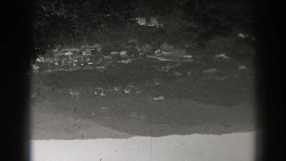 Inverted 8mm view from 1938 New Jersey, showing a small settlement and wooded mountain base from afar.