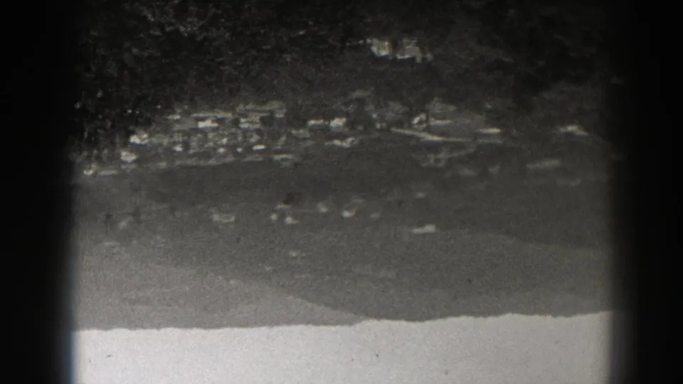 1938 New Jersey 8mm frame showing a very dim distant landscape with faint lights, dark upper shapes, and a pale foreground strip.
