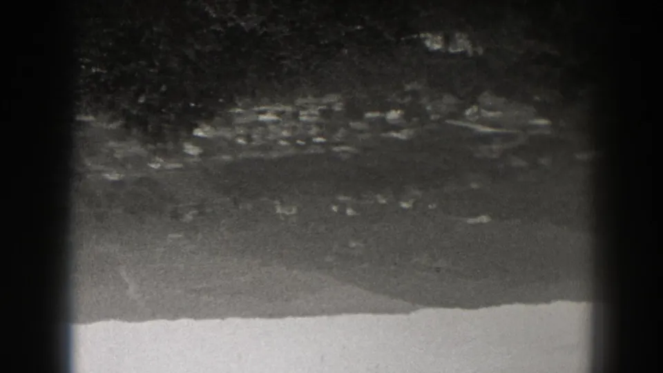 1938 New Jersey home-movie frame with scattered distant lights, indistinct dark landforms, and a bright foreground edge.