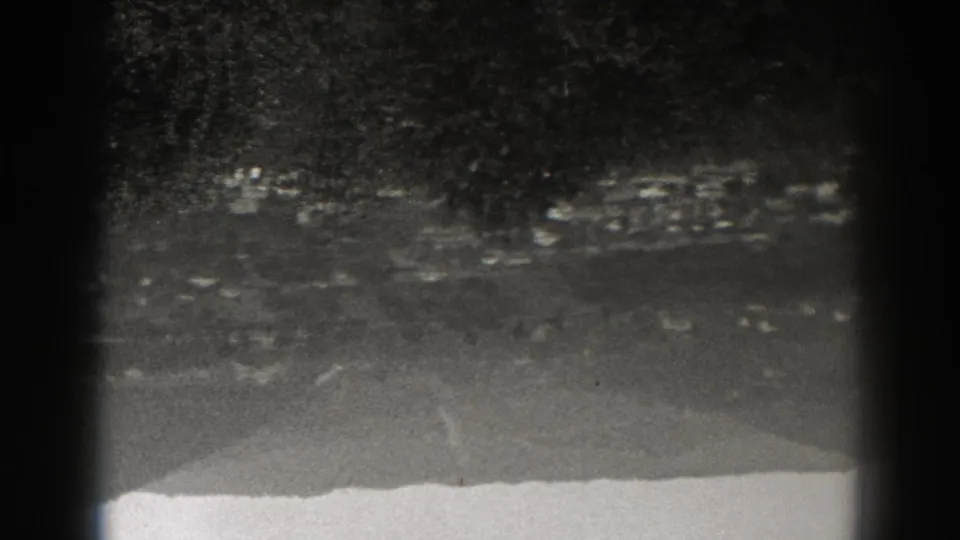 Upside-down 1938 New Jersey home-movie frame with scattered buildings, wooded slopes, and a pale road through the town.