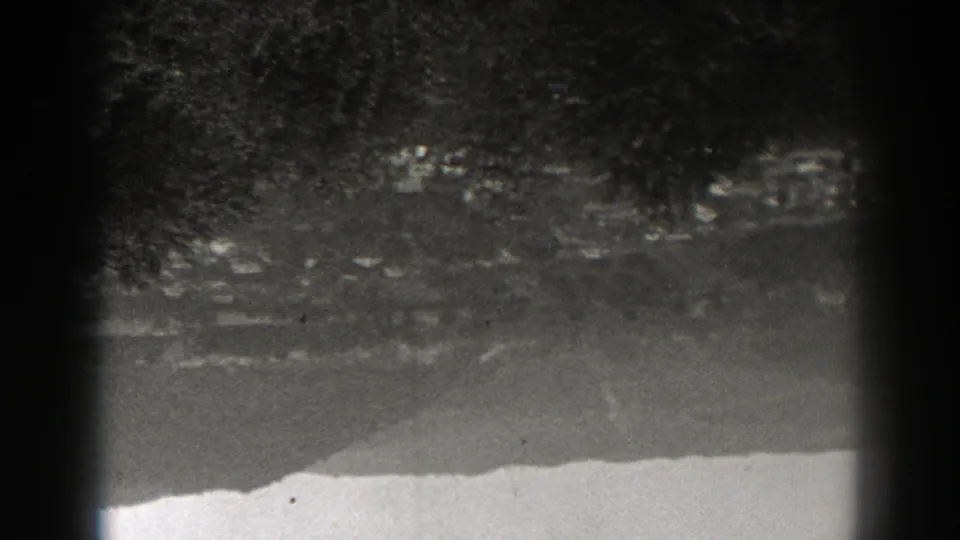 Upside-down 1938 New Jersey frame with soft-focus trees, distant buildings, hillside roads, and heavy dark film-edge shadow.