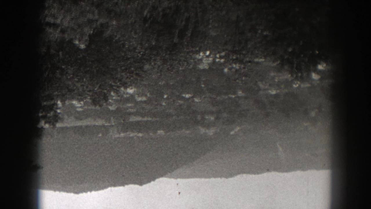 Black-and-white 1938 New Jersey lake view with soft tree reflections, a bright shoreline band, and visible 8mm gate shadowing.