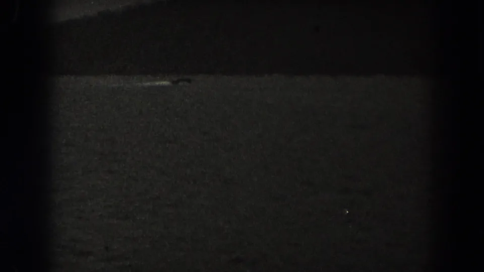 Low-light 1938 New Jersey frame with dark water, a faint pale streak, and a small dark shape that may be a boat.
