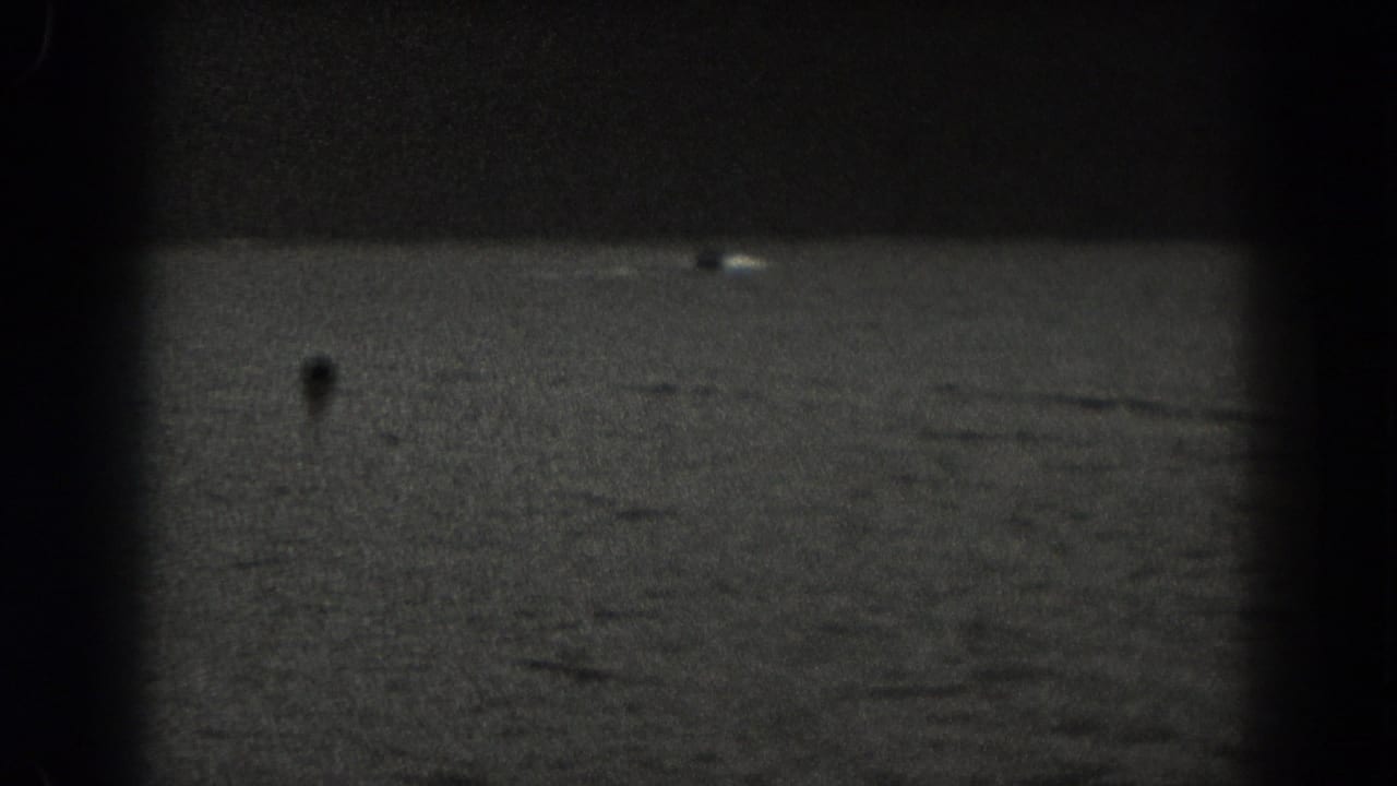Dark rippling water with a tiny distant boat shape near the left side.