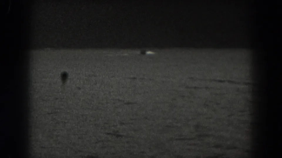 1938 New Jersey 8mm frame showing dark water and a barely visible small boat silhouette in low light.