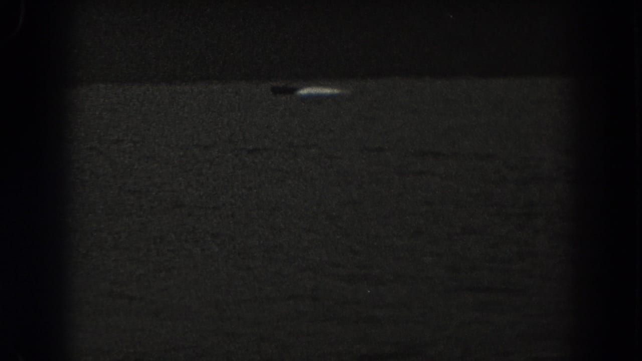 1938 New Jersey 8mm frame with a small boat and pale wake or reflection on dark open water.