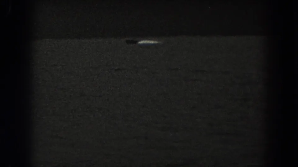 1938 New Jersey 8mm frame with a small boat and pale wake or reflection on dark open water.