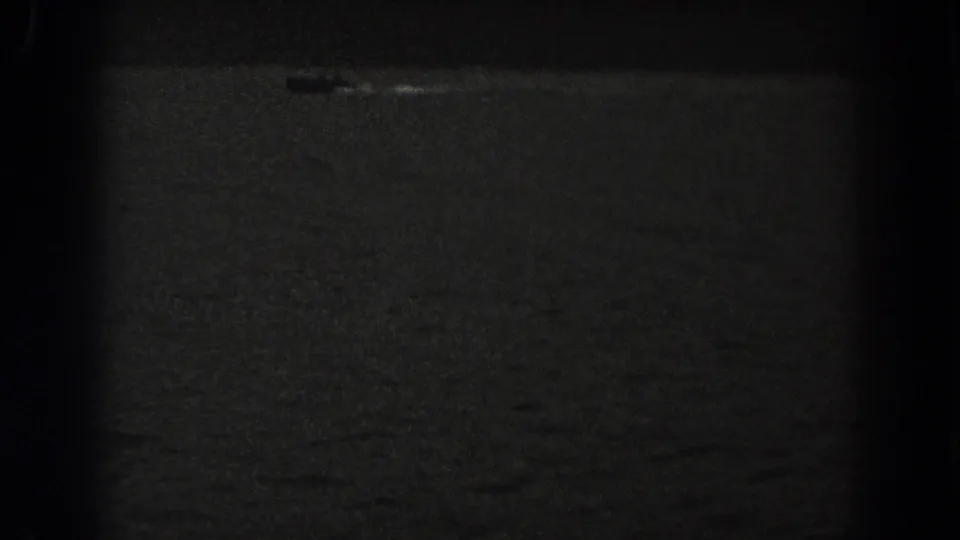 1938 New Jersey 8mm frame showing a small boat on dark lake water, with heavy vignetting and a faint wake.