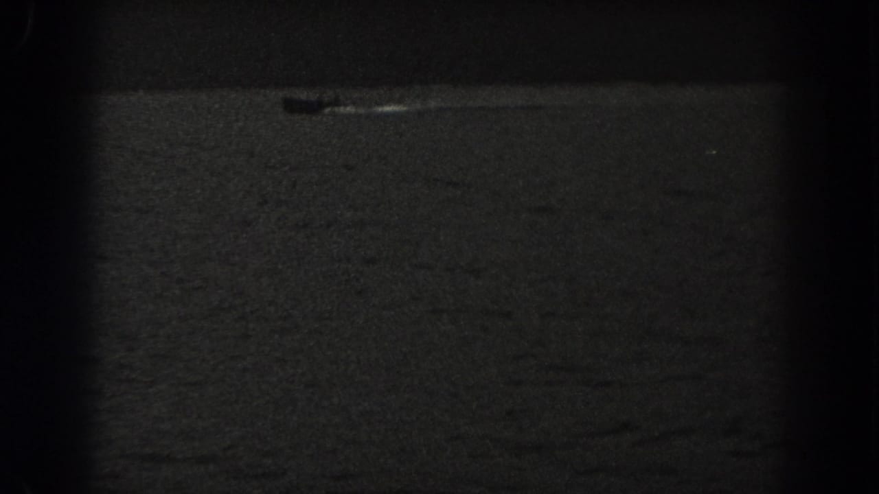 A small boat appears on a dark New Jersey lake in this grainy 1938 8mm home-movie frame.