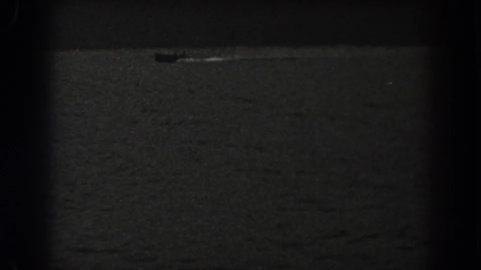 A small boat appears on a dark New Jersey lake in this grainy 1938 8mm home-movie frame.
