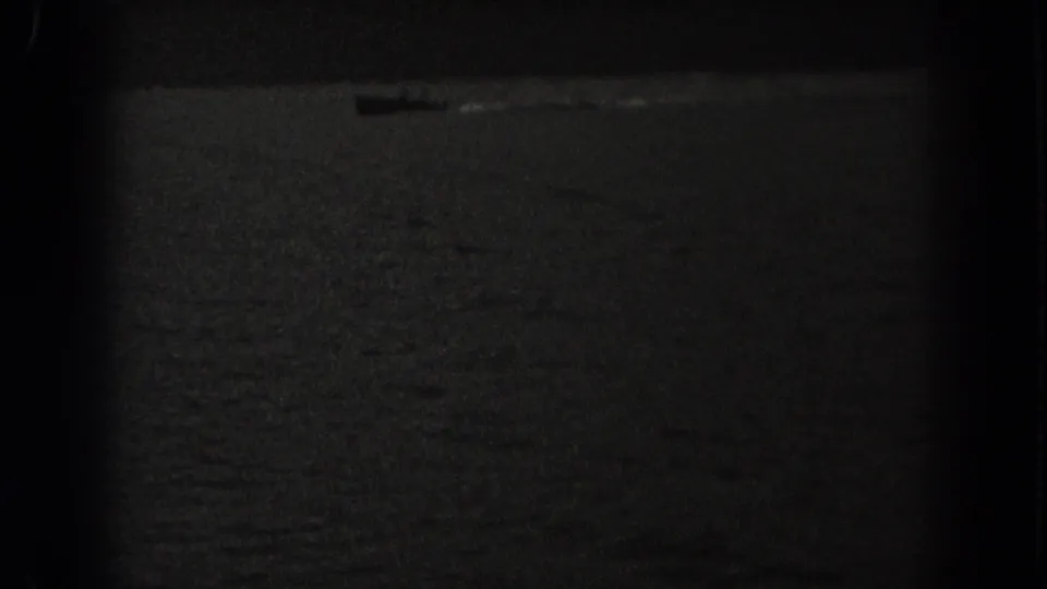 Low-light 8mm frame of a small boat moving across a dark lake, with New Jersey location supported by clip metadata.