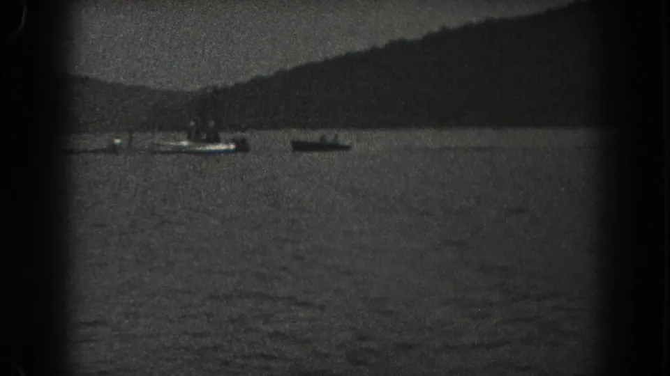 1938 New Jersey home-movie frame with two small boats on lake water and a tree-lined hillside in the background.