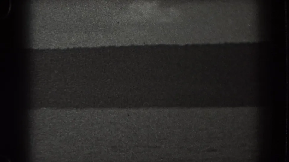 1938 New Jersey boat-view frame showing rippled lake water, a shadowed shoreline, and the rounded border of the 8mm film gate.