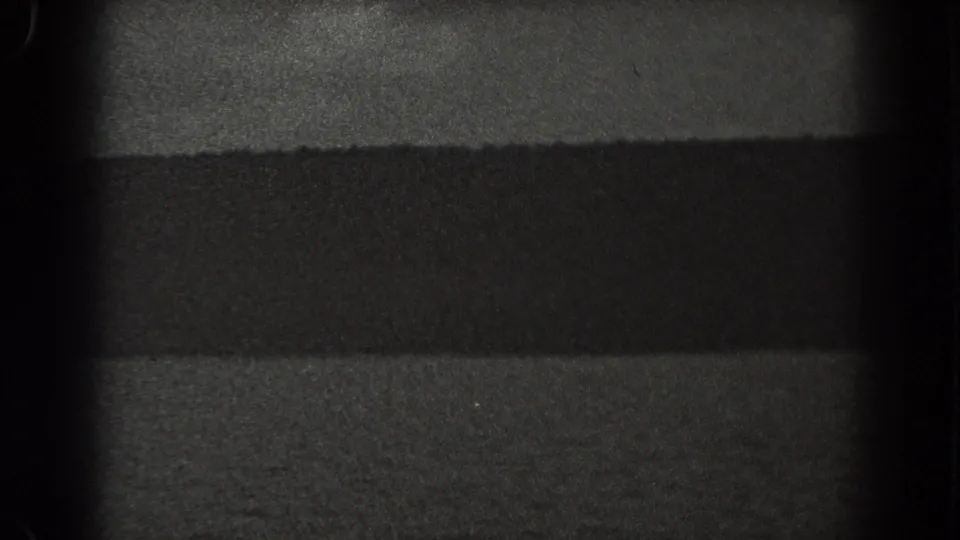1938 New Jersey 8mm frame showing a dark shoreline or hillside across calm water beneath a dim night sky.