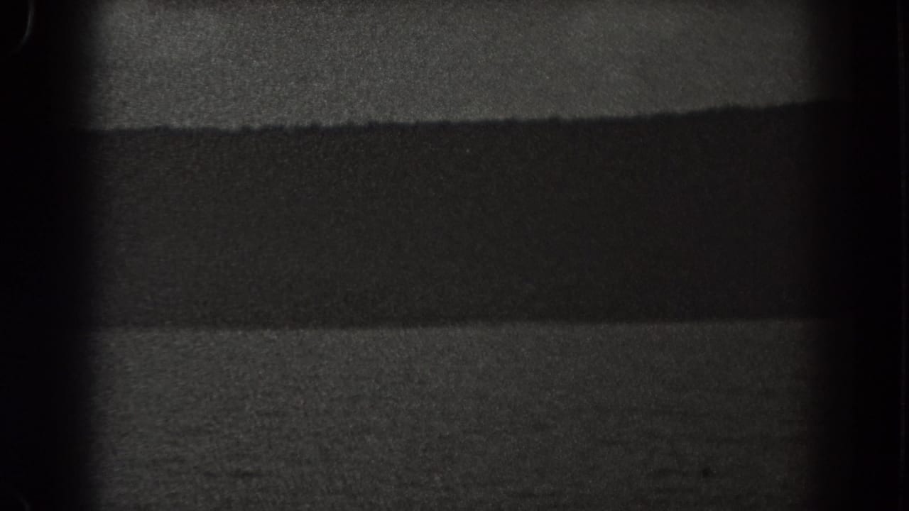 1938 New Jersey coastal frame with calm water, a dark ridge line, and soft grain in low night exposure.