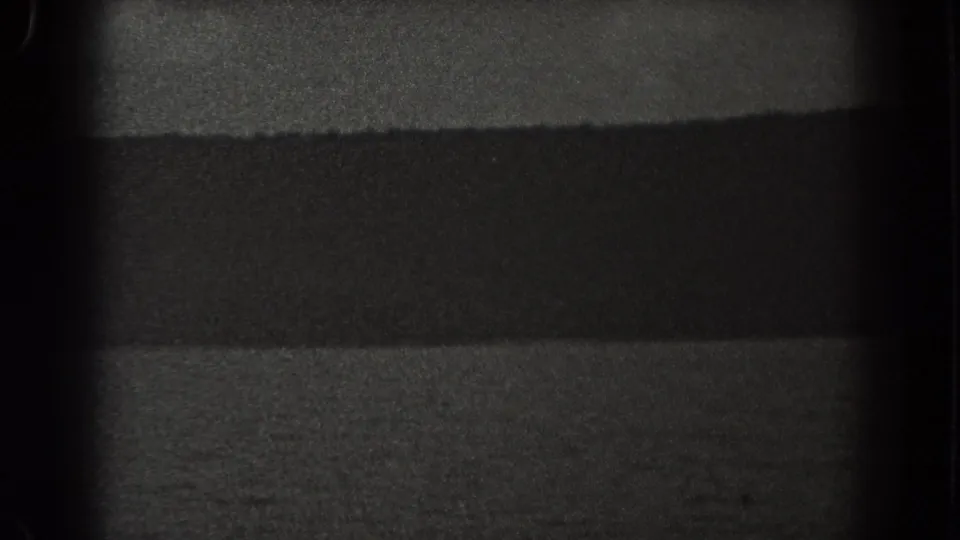 1938 New Jersey coastal frame with calm water, a dark ridge line, and soft grain in low night exposure.