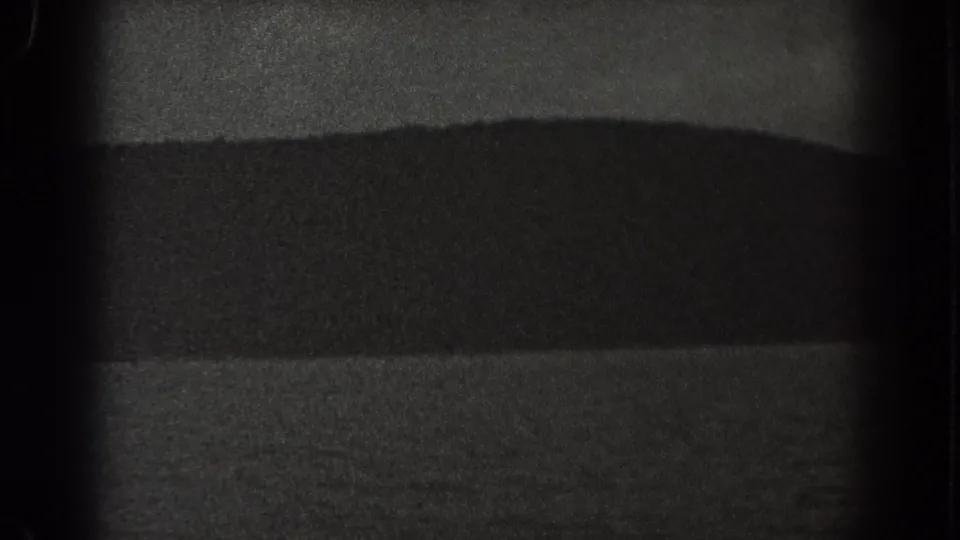 1938 New Jersey 8mm frame of a dark hillside or mountain silhouette with faint water and sky bands.