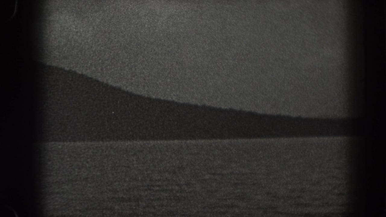 Water and a long dark shoreline ridge beneath a bright sky.