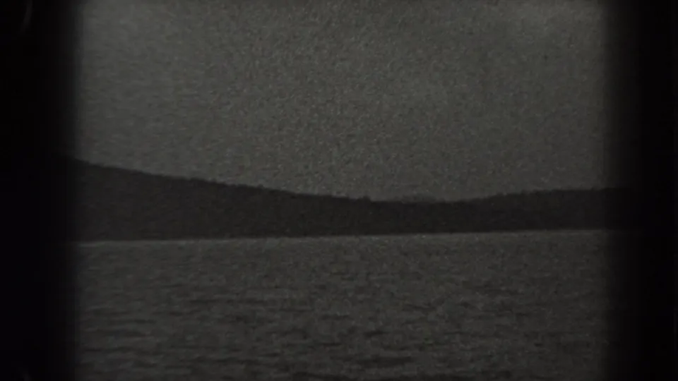 1938 New Jersey 8mm landscape frame with textured water below a low distant ridge and blank sky.