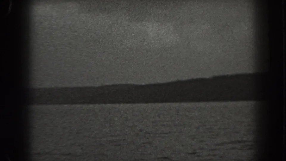 1938 New Jersey 8mm frame with rippled water in the foreground and a dark, undulating wooded shoreline beyond.