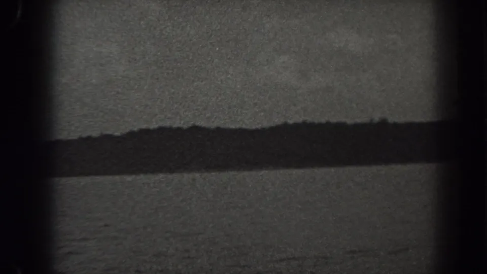 Late frame from a 1938 New Jersey 8mm lake view, showing water, wooded shore, low hills, and cloudy sky.