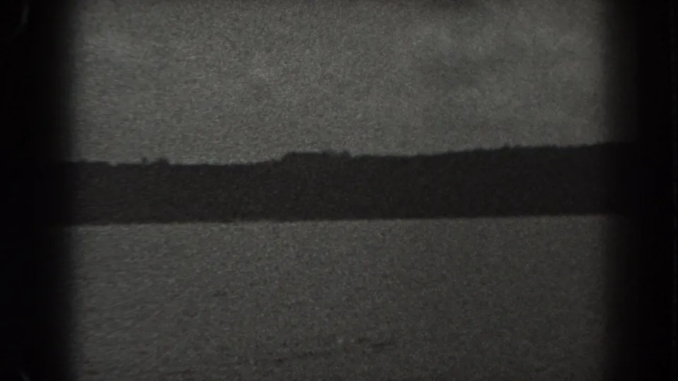 Black-and-white 8mm lake view from New Jersey in 1938, with textured water, distant shoreline, pale sky, and pronounced film border artifacts.